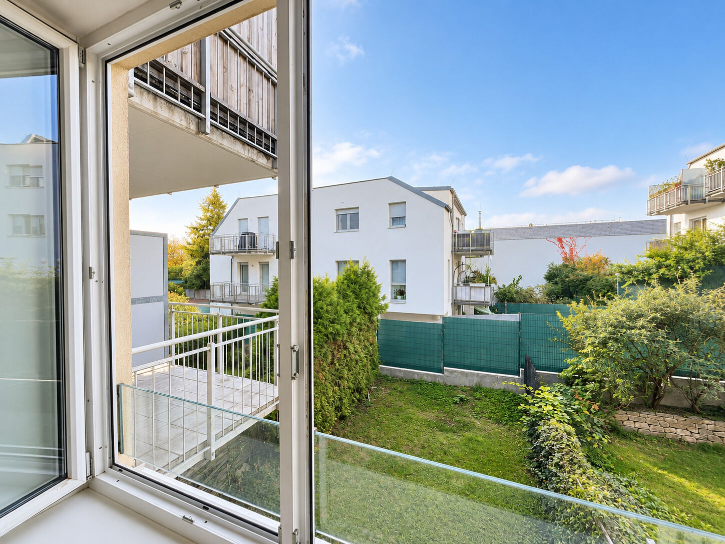 Blick aus dem offenen Fenster in den grünen Innenhof